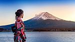 Asian Woman Wearing Japanese Traditional Kimono At Fuji Mountain. Sunset At Kawaguchiko Lake In Japan Stock Photo