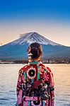 Asian Woman Wearing Japanese Traditional Kimono At Fuji Mountain. Sunset At Kawaguchiko Lake In Japan Stock Photo