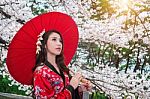 Asian Woman Wearing Traditional Japanese Kimono With Red Umbrella And Cherry Blossom Stock Photo