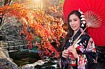 Asian Woman Wearing Traditional Japanese Kimono With Red Umbrella In Autumn Stock Photo