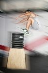 Athletic Man Jumping Over A Lot Of Weights Stock Photo