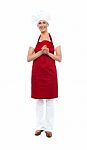 Attractive Female Chef In Red Apron And Toque Stock Photo