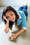 Beautiful Brunette Girl Who Is Lying On The Floor And Drinking C Stock Photo