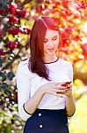 Beautiful Girl Typing Text Message On Her Smart Phone In The Gar Stock Photo