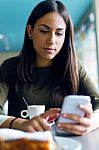 Beautiful Girl Using Her Mobile Phone In Cafe Stock Photo