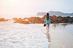 Beautiful Girl Walking On The Beach At Sunset Stock Photo