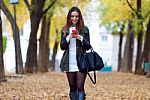 Beautiful Girl Walking With Mobile Phone In Autumn Stock Photo