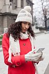 Beautiful Woman In Red Coat And Wool Cap And Gloves With Smartph Stock Photo