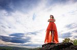 Beautiful Woman Wear Red Evening Dress Stand On The Rocks Over M Stock Photo