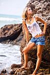 Beautiful Young Blonde Woman Posing Outdoor At The Rocky Sea Shore Stock Photo