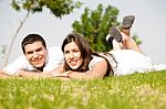 Beautiful Young Couple Lie Down On Grass Stock Photo