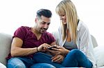 Beautiful Young Couple Using Mobile Phone At Home Stock Photo