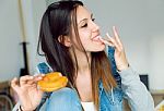 Beautiful Young Woman Eating Donuts At Home Stock Photo