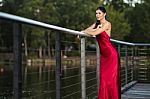 Beautiful Young Woman In The Gardens Wearing A Long Silk Red Dress Stock Photo