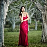 Beautiful Young Woman In The Gardens Wearing A Long Silk Red Dress Stock Photo