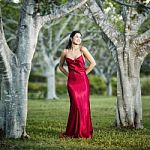 Beautiful Young Woman In The Gardens Wearing A Long Silk Red Dress Stock Photo