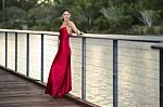 Beautiful Young Woman In The Gardens Wearing A Long Silk Red Dress Stock Photo