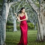 Beautiful Young Woman In The Gardens Wearing A Long Silk Red Dress Stock Photo