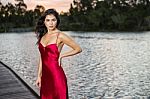 Beautiful Young Woman In The Gardens Wearing A Long Silk Red Dress Stock Photo