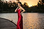 Beautiful Young Woman In The Gardens Wearing A Long Silk Red Dress Stock Photo