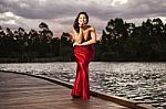 Beautiful Young Woman In The Gardens Wearing A Long Silk Red Dress Stock Photo