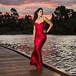 Beautiful Young Woman In The Gardens Wearing A Long Silk Red Dress Stock Photo