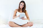 Beautiful Young Woman Using Her Digital Tablet Lying On Bed Stock Photo