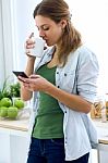 Beautiful Young Woman Using Her Mobile Phone And Enjoying Breakf Stock Photo