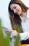 Beautiful Young Woman Using Her Mobile Phone At Cafe Shop Stock Photo