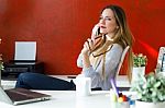 Beautiful Young Woman Using Her Mobile Phone In The Office Stock Photo