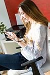 Beautiful Young Woman Using Her Mobile Phone In The Office Stock Photo