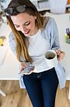 Beautiful Young Woman Using Her Mobile Phone In The Office Stock Photo