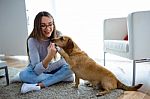 Beautiful Young Woman With Dog Playing At Home Stock Photo