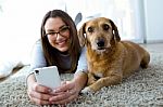 Beautiful Young Woman With Her Dog Using Mobile Phone At Home Stock Photo