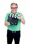 Bespectacled Elderly Man Holding A Clapperboard Stock Photo