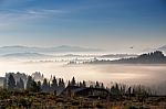 Bird Flying Over Hills And Village. Foggy Morning In Mountains Stock Photo