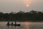 Blurred Image Of People Paddling Boat In Pond With Sunset In Par Stock Photo