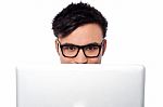 Boy Trying To Hide His Face Behind Laptop Stock Photo