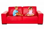 Brother And Sister On Red Sofa Stock Photo