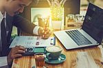 Business Man Sitting On A Calculator To Figure Out In A Coffee S Stock Photo