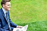 Businessman Reading Newspapers In Park Stock Photo