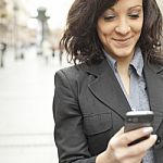 Businesswoman With Smartphone Walking On Street Stock Photo