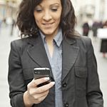 Businesswoman With Smartphone Walking On Street. Phone In Focus Stock Photo