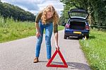 Caucasian Woman Placing Warning Triangle On Rural Road Stock Photo