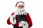 Cheerful Aged Santa Posing With A Clapperboard Stock Photo