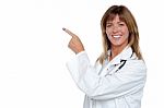Cheerful Female Doctor Pointing Away Stock Photo
