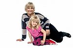 Cheerful Mum And Daughter Sitting On Studio Floor Stock Photo