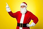 Cheerful Santa Pointing Away. Copy Space Concept Stock Photo