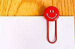 Close Up Of A  Red Paper Clip And White Paper On Wood Table Stock Photo