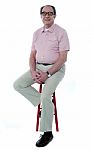 Confident Old Man Resting On Stool Stock Photo